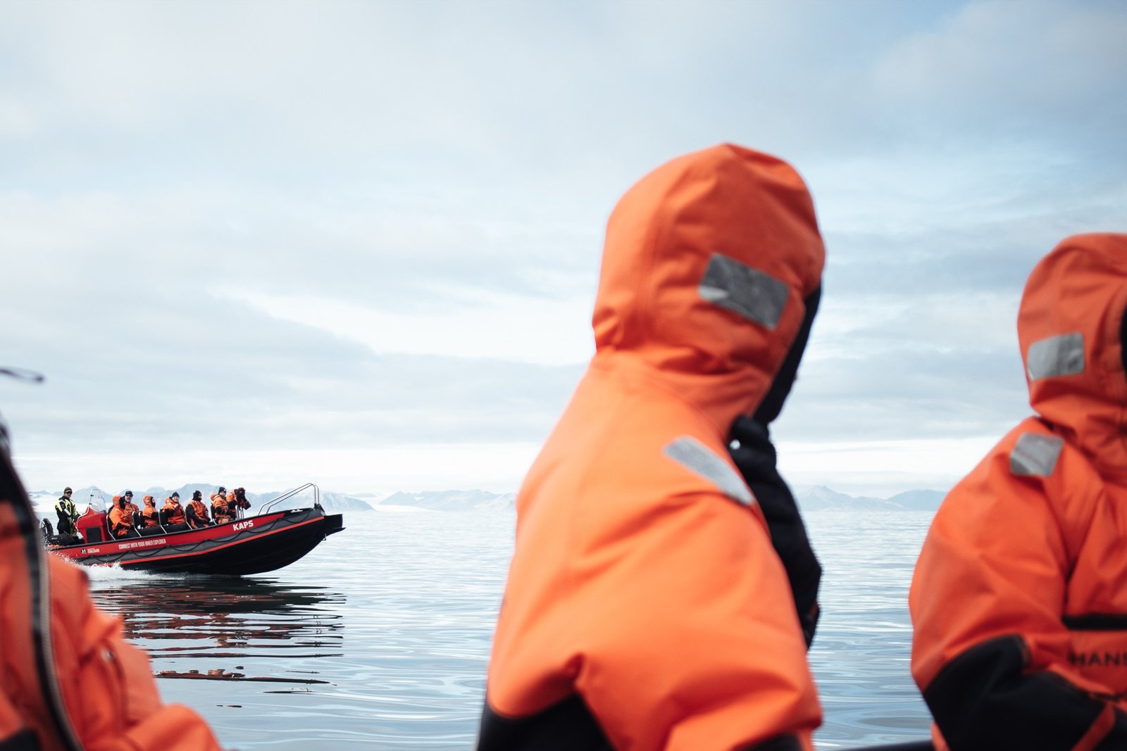 Students in orange survival suits beside rubber boats